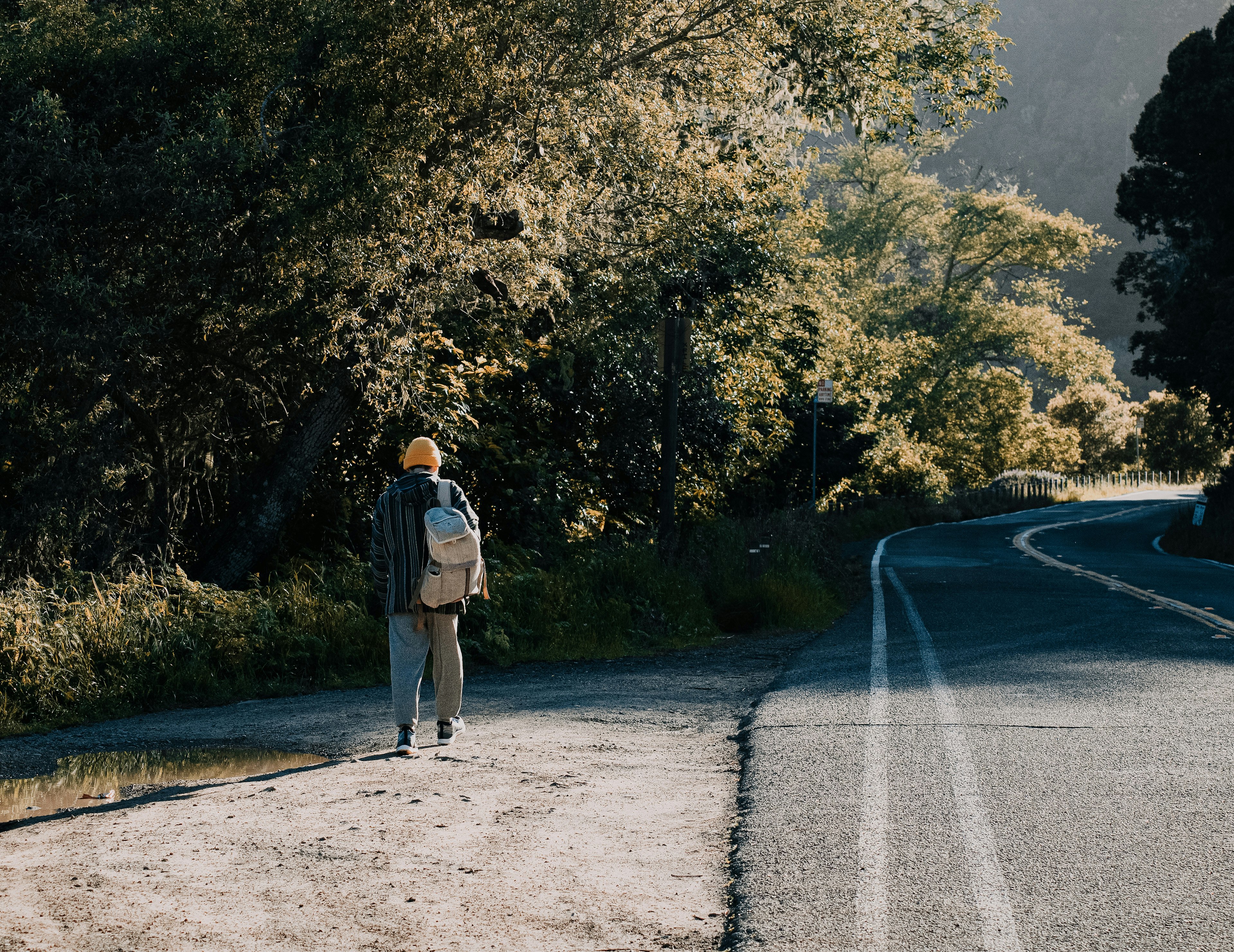 man in gray jacket and brown pants standing on gray asphalt road during daytime